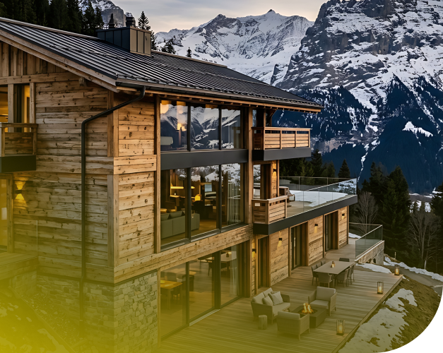 Modernes Chalet aus Holz und Glas vor einer verschneiten Berglandschaft