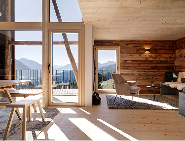 Holzverkleideter Wohnraum mit Glastür und Blick auf die Berge