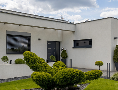 Weißer Bungalow mit Formschnitt-Gehölzen im Vorgarten