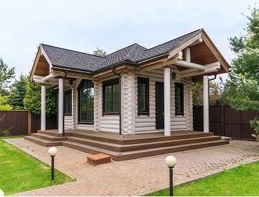 Kleines helles Blockhaus mit Säulenveranda und gepflastertem Vorplatz