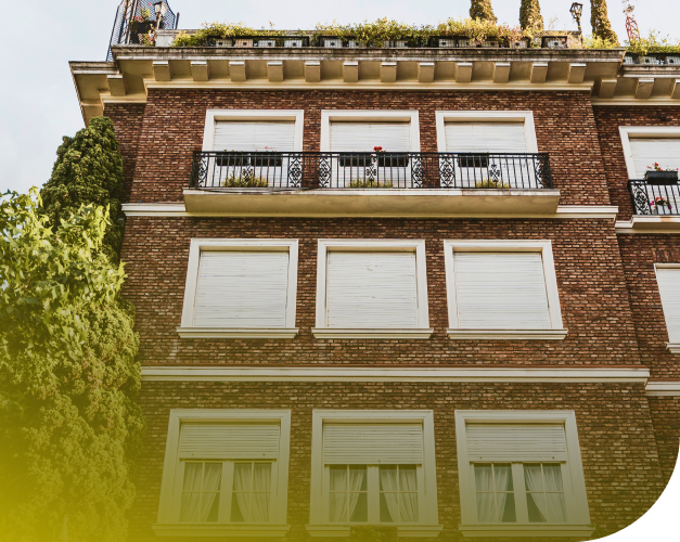 Mehrfamilienhaus aus Backstein mit Balkonen und begrüntem Dach von unten fotografiert