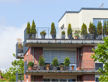 Klinker-Mehrfamilienhaus mit bepflanzten Balkonen und Dachterrasse