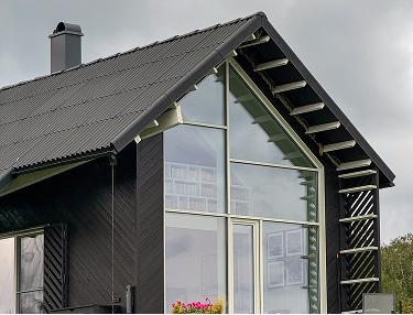 Dunkles Haus mit Satteldach und raumhohem Glasgiebel