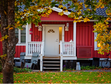 Rotes Schwedenhaus mit weißer Veranda im Herbstlaub