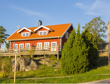 Rotes Schwedenhaus mit orangem Dach auf einer Anhöhe