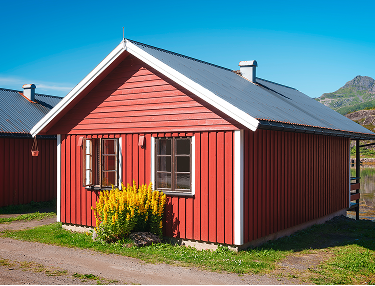 Rotes Holzhaus mit weißen Fenstern und blühendem Ginster