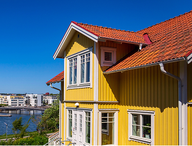 Gelbes Schwedenhaus mit weißen Fenstern und rotem Ziegeldach