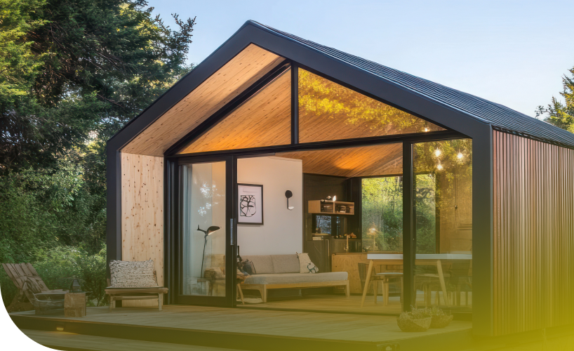 Modernes Tiny Haus aus Holz mit Satteldach und großer Glasfront in einem Waldgrundstück
