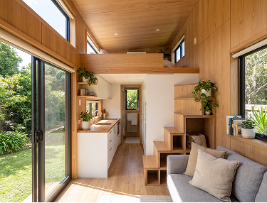 Innenraum eines Tiny House mit Küchenzeile, Treppe zum Schlafboden und Sofa